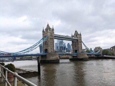 Londra, İngiltere - 13 Mayıs 2024: Iconic Tower Bridge, Londra 'daki Thames Nehri boyunca uzanır, modern Londra şehrinin finans bölgesi gökyüzü bulutlu, Butlers Wharf' ın manzarası altında yükselir