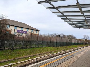 Londra, İngiltere - 11 Mart 2023: Bir Premier Inn oteli Beckton DLR istasyonundan izlenen bir demiryolu hattının yanında bulutlu bir gökyüzü altında duruyor