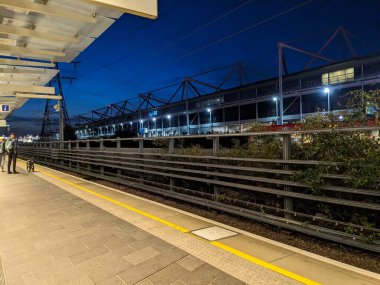 Londra, İngiltere - 10 Ekim 2023: Gümrük Evi Elizabeth Hattı istasyonunda gün ağarırken banliyö ulaşım altyapısını vurgulayan parlak ışıklı bir platformda bekleyenler