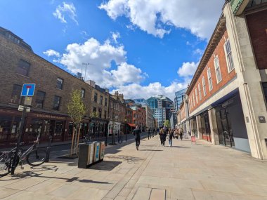 Londra, İngiltere - 3 Nisan 2022: İnsanlar Spitalfields 'taki yayaya çıkmış Brushfield Caddesi boyunca yürüyor, tarihi bir alan, geleneksel tuğla binalar ve modern şehir gökdelenlerinin karışımı.