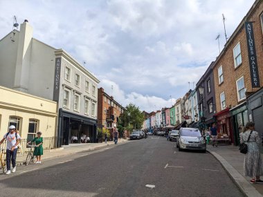 Londra, İngiltere - Eylül 04 2022: Notting Hill 'deki Portobello Yolu boyunca yürüyen yayalar, antika dükkanları ve renkli teraslı evleriyle tanınan canlı bir pazar caddesi.