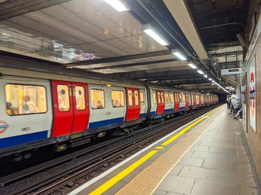 Londra, İngiltere - 26 Eylül 2021: Bir Londra metro treni ışıklandırılmış Liverpool Caddesi İstasyonuna ulaşır, yolcular bekler ve trenler hareketlerini dinamik bir bulanıklıkla yakalar