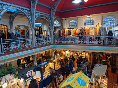 Londra, İngiltere - 27 Kasım 2021: Alışverişçiler, Londra 'nın el sanatları, giysiler ve benzersiz hediyeler için popüler bir tatil yeri olan tarihi Camden Pazarı' nın hareketli Viktorya dönemi mimarisinde hareketli tezgahlara göz atıyorlar