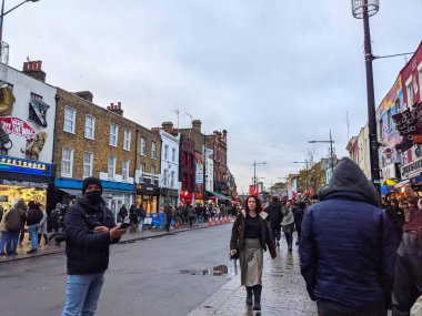 Londra, İngiltere - 27 Kasım 2021: Camden High Street 'in ıslak kaldırımları boyunca hareketli bir kalabalık yürür, ilginç dükkan cepheleri ve hareketli alternatif atmosferiyle ünlüdür.