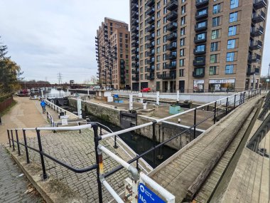 Londra, İngiltere - 16 Aralık 2021: Bir bisikletçi Tottenham Lock 'un Lea Nehri' nin sahil yolu boyunca ilerlerken, modern apartmanlar kentsel yenilenmeyi yansıtıyor.