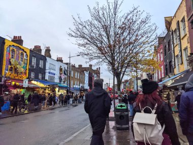 Londra, İngiltere - 27 Kasım 2021: Camden High Street 'in ıslak kaldırımlarında yürüyen kalabalık, bulutlu bir gökyüzü altında ünlü market tezgahlarına ve eklektik mağazalara göz atıyor