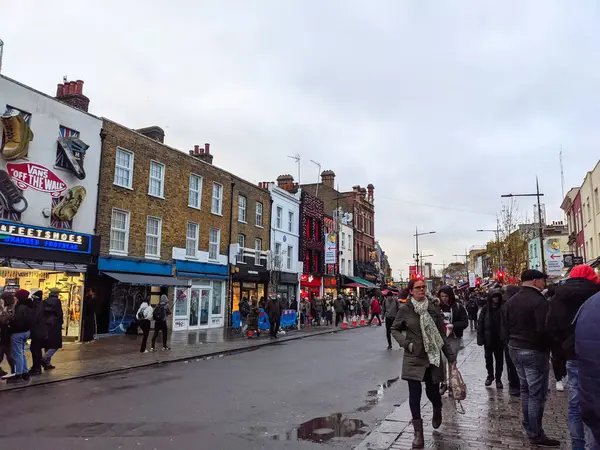 Londra, İngiltere - 27 Kasım 2021: Çeşitli müşteriler bulutlu bir öğleden sonra ıslak bir Camden High Street boyunca eklektik mağazaları ve işlek alternatif pazar tezgahlarını keşfediyor