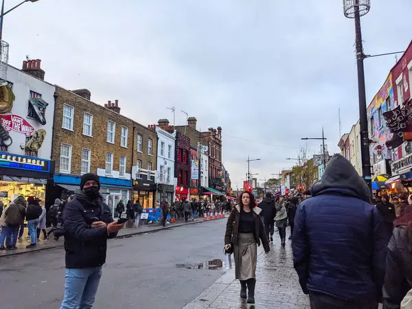 Londra, İngiltere - 27 Kasım 2021: Camden High Street 'in ıslak kaldırımları boyunca hareketli bir kalabalık yürür, ilginç dükkan cepheleri ve hareketli alternatif atmosferiyle ünlüdür.