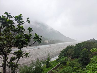 Taroko, Tayvan - 26 Kasım 2022: Geniş açılı bir manzara Taroko Ulusal Parkı 'nın sakin ve puslu manzarasını yakalar, Liwu nehrinin bulutlarla kaplı yeşil orman dağlarıyla çevrili kayalık bir yatakta kıvrılışını gösterir.