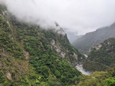 Taroko, Tayvan - 26 Kasım 2022: Yoğun sis ve bulutlar, aşağıdaki görkemli vadide akan kıvrımlı bir nehirle Taroko Ulusal Parkı 'nın yüksek, yemyeşil dağlarını kucaklıyor