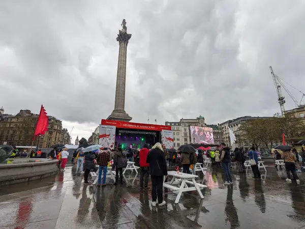 Londra, İngiltere - 2023.04.23: Trafalgar Meydanı 'nda St Georges Günü kutlamaları sahnede bir grup sahne alıyor ve seyirci yağmurda müziğin keyfini çıkarıyor, Nelsons Sütunu arkada bulutlu bir gökyüzünün altında.