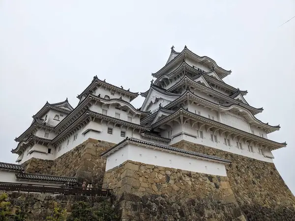 Himeji, Japonya - 12.19.2023: Himeji Şatosu 'nun yüksek taş duvarındaki Ana Kale cephesi