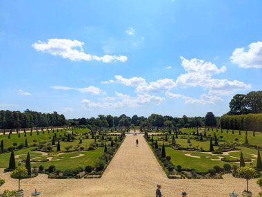 Londra, İngiltere - 07.19.2024: Hampton Court Palace 'daki iyi bakımlı Privy Garden' a ziyaretçiler açık mavi gökyüzü altında güneş ışığıyla yürüyorlar