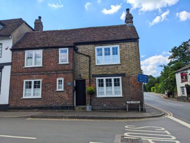 Meopham, İngiltere - 06.05.2024: Uçsuz bucaksız çatılı ve tuğladan yapılma bacaları olan, caddede yürüyen araba ve yayalar olmayan sıradan bir köy tuğlası ev