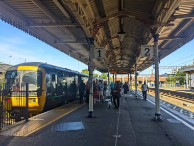 Windsor, İngiltere - 2022.07.16: Platformda yürüyen ve güneşli bir günde açık bir gökyüzü altında Windsor 'a giden Great Western Demiryolu trenine binen yolcular.