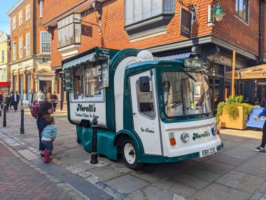 Canterbury, UK - April 19 2025: A classic Morellis ice cream truck is parked on a bustling cobblestone street in Canterbury, serving customers on a sunny spring day