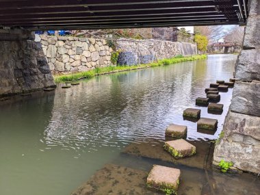 Omihachiman, Japonya - 12.20.2023: Hachimanbori su yolundaki geleneksel ahşap köprünün altında turistler olmadan bulutlu mavi gökyüzünün altında başka bir ahşap köprü.