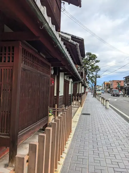 Omihachiman, Japonya - 12.20.2023: Tarihi ahşap binalarla dolu geleneksel bir Japon caddesi ve bulutlu bir gökyüzü altında sakin bir şehir manzarasını gösteren iyi korunmuş bir kaldırım