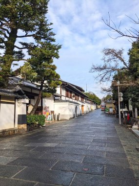 Kyoto, Japonya - 2023.12.16: Nene-no-michi 'de geleneksel Japon mimarisi ve ağaçlarının yanında güneş ışığıyla birlikte mavi gökyüzü altında sessiz bir sahne