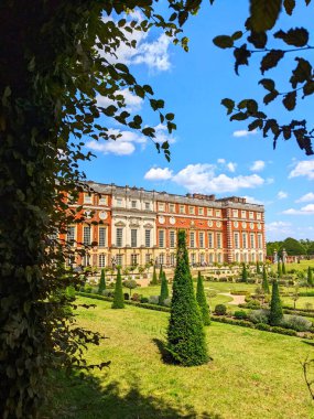 Londra, İngiltere - 07.19.2024: Hampton Court Palace 'daki Privy Garden ile Güney Cephesi, açık mavi gökyüzü altında güneş ışığı ve bulutlar altında çiçek tüneli manzarası