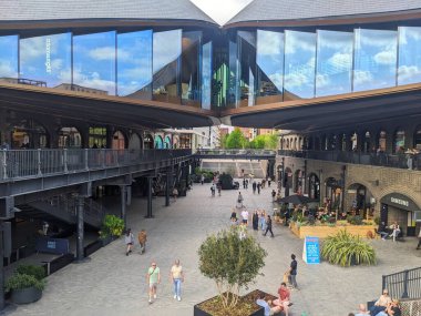 Londra, İngiltere - 03 Mayıs 2025: Coal Drops Yard meydanındaki ziyaretçiler, ikonik öpme çatıları olan Viktorya dönemi simgesi, şimdi Regents Canal 'ın yanında canlı bir alışveriş ve yemek merkezi.