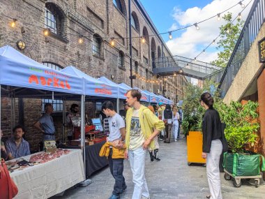 Londra, İngiltere - 3 Mayıs 2025: Viktorya dönemi mimarisi ile hareketli bir alışveriş merkezi olan Kömür Devreleri Yard 'daki popüler Lower Stable Street Market' te çeşitli bir kalabalık esnaf tezgahlarına göz attı