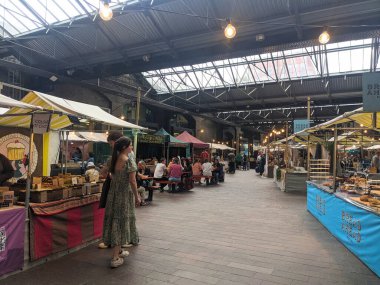 Londra, İngiltere - 3 Mayıs 2025: Coal Drops Yard 'daki ikonik çatı yapısı altındaki tepe örtüsü pazarının canlı atmosferinin tadını çıkaran kalabalık