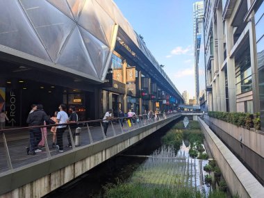 Londra, İngiltere - 11 Mayıs 2025: Çağdaş mimarisi ve canlı bir atmosferi olan modern bir finans bölgesi olan Canary Wharf 'taki Crossrail Place rıhtımında insanlar yürüyüp rahatlıyor