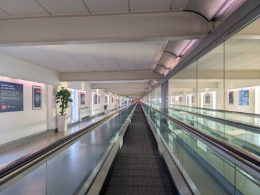 Londra, İngiltere - 21 Mayıs 2025: Simetrik çizgilere sahip boş bir yürüyüş yolu, küresel seyahat merkezlerinden biri olan Heathrow Havaalanı T3 'ün sessiz ve modern bir koridorunda kaybolan nokta perspektifi yaratır.