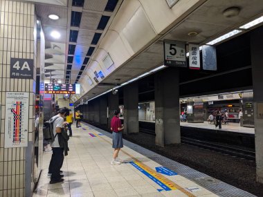 Taipei, Tayvan - 23 Mayıs 2025: Yolcular, kentteki kentsel yolculuklarına rehberlik eden iki dilli işaretler ve dijital göstergelerle dolu bir yeraltı tren peronunda tren bağlantılarını bekliyorlar