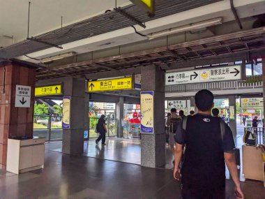 Hualien, Tayvan - 23 Mayıs 2025: Yolcular ve gezginler, Çince ve İngilizce iki dilli işaretleri takip ederek doğu çıkışı ve kente doğru bir tren istasyonunun ana koridorundan geçtiler.