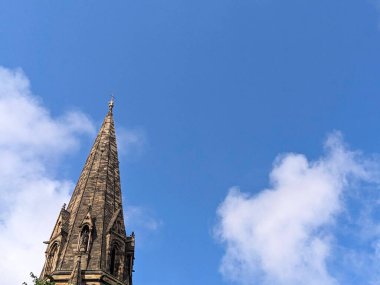 Edinburgh, İngiltere - 16 Temmuz 2025: Gotik Diriliş mimarisinin bir örneği olan Aziz Marys Katolik Katedrali 'nin taş kulesi, dağınık bulutlu mavi gökyüzüne karşı alçak bir açıdan bakıldığında