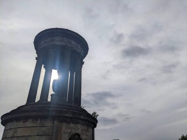 Edinburgh, İskoçya - 15 Temmuz 2025: Calton Hill 'deki Dugald Stewart Anıtı' nın alçak açılı görüntüsü, gri bir gökyüzüne karşı güneş ışığıyla aydınlandı