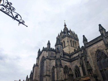 Edinburgh, İskoçya - 17 Temmuz 2025: Düşük açı, tarihi Gotik cepheyi ve St. Giles Katedrali 'nin ikonik taç çan kulesini dramatik bulutlu gökyüzüne yansıtıyor
