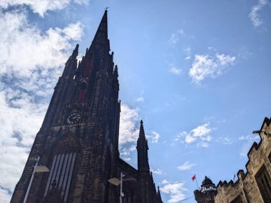 Edinburgh, İskoçya, İngiltere - 16 Temmuz 2025: The Hub 'un yükselen Gotik kulesi, Royal Mile' daki tarihi bir sanat merkezi, Eski Şehir 'de beyaz bulutları olan açık mavi bir gökyüzüne karşı duruyor.