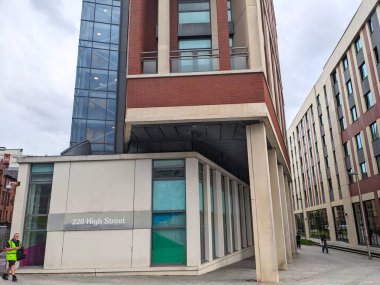 Glasgow, İskoçya - 14 Temmuz 2025: Yayalar bulutlu bir gökyüzü altında tuğla, cam ve beton mimariden oluşan 220 High Street 'in modern cephesinin önünden geçtiler
