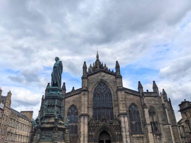Edinburgh, İngiltere - 17 Temmuz 2025: St. Giles Katedrali 'nin görkemli Gotik cephesi ve Buccleuch Dükü tarihi Royal Mile üzerindeki dramatik bulutlu gökyüzüne karşı dimdik ayakta duruyorlar
