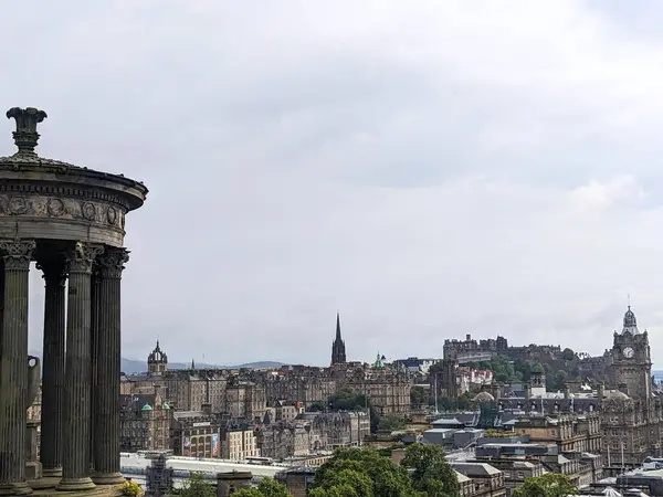 Edinburgh, İskoçya - 15 Temmuz 2025: Calton Hill 'den panoramik şehir manzarası, Dugald Stewart Anıtı, Edinburgh Kalesi ve Eski Şehir silueti bulutlu bir gökyüzü altında