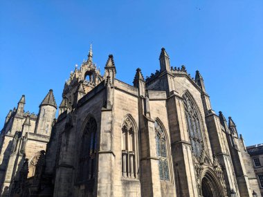 Edinburgh, İngiltere - 16 Temmuz 2025: Kraliyet Mil 'inin tarihi bir simgesi olan St. Giles Katedrali' nin karmaşık Gotik cephesi, berrak ve bulutsuz bir mavi gökyüzüne karşı kurulmuştur.