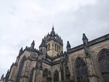 Edinburgh, İskoçya, İngiltere - 17 Temmuz 2025: Düşük açılı bir manzara, bulutlu bir gökyüzü altında St. Giles Katedrali 'nin karmaşık Gotik mimarisini ve ünlü taç çan kulesini yakalar.