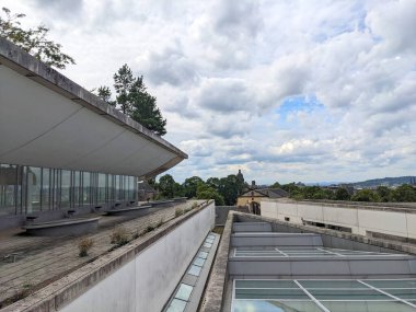 Edinburgh, İskoçya - 17 Temmuz 2025: Ulusal İskoçya Müzesi 'nin çağdaş bir çatısından yükselen manzara, bulutlu bir gökyüzünün altındaki tarihi Eski Şehir silüetiyle çelişen beton bir mimari.