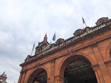 Glasgow, İskoçya - 13 Temmuz 2025: Düşük açılı bir perspektif ünlü Kelvingrove Sanat Galerisi ve Müzesi 'nin süslü kırmızı kumtaşı girişini bulutlu bir gökyüzü altında yakalar