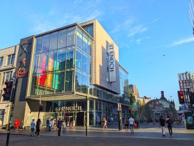 Glasgow, İskoçya - 12 Temmuz 2025: Müşteriler ve banliyö sakinleri açık bir gökyüzünün altında güneşli bir günde St. Enoch Meydanı 'nda modern St Enoch Merkezi ve metro istasyonunun geleceksel cam tepe örtüsünün önünden geçtiler