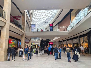 Edinburgh, İskoçya - 15 Temmuz 2025: Müşteriler, büyük cam bir atriyum çatısı olan popüler bir perakende ve eğlence merkezi olan modern St. James Quarter 'ın çok katlı iç kesimlerinde yürüyor