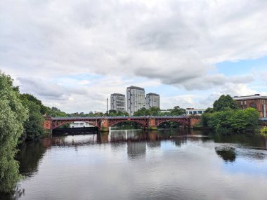 Glasgow, İskoçya - 14 Temmuz 2025: Viktorya dönemi Weir ve boru köprüsü, nehrin yukarısındaki su seviyesini kontrol etmek için nehirden geçen kapılarla suya yansıyan modern daireler