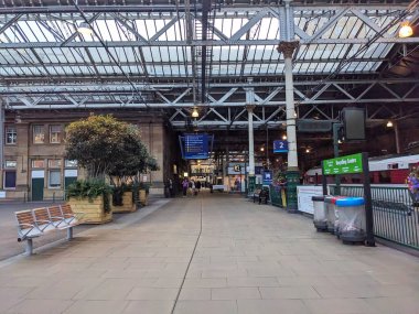 Edinburgh, İngiltere - 18 Temmuz 2025: Tarihi Edinburgh Waverley tren istasyonundaki bir platformda yürüyen yolcular ve banliyö sakinleri, Viktorya dönemi mimarisi ve büyük cam çatılı bir ulaşım merkezi
