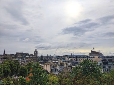 Edinburgh, İskoçya, İngiltere - 15 Temmuz 2025: Şehir merkezinin üzerindeki Calton Hill 'den yükseltilmiş bir manzara, yemyeşil verimli gökyüzünün altında kurulmuş tarihi kuleleri ve modern binaları gözler önüne seriyor