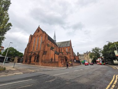 Glasgow, İskoçya - 14 Temmuz 2025: Bulutlu bir günde Castle Caddesi 'nde şehir trafiği ve yayalar ile Strathclyde Üniversitesi' nin bir parçası olan Gotik Uyanış Baronluk Salonu 'nun geniş açılı bir görüntüsü