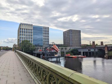 Glasgow, İskoçya - 14 Temmuz 2025: Clyde Nehri 'nin karşısındaki Albert Köprüsü' nden modern Glasgow College Riverside Kampüsü 'nü tarihi Union Köprüsü' nün yanında bulutlu bir gökyüzünün altında gösteren manzara
