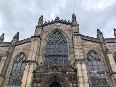 Edinburgh, İskoçya - 17 Temmuz 2025: Düşük açılı bir manzara, bulutlu bir gökyüzü altında tarihi Royal Mile üzerindeki St. Giles Katedrali 'nin karmaşık Gotik cephesini ve boyalı camlarını yakalar.